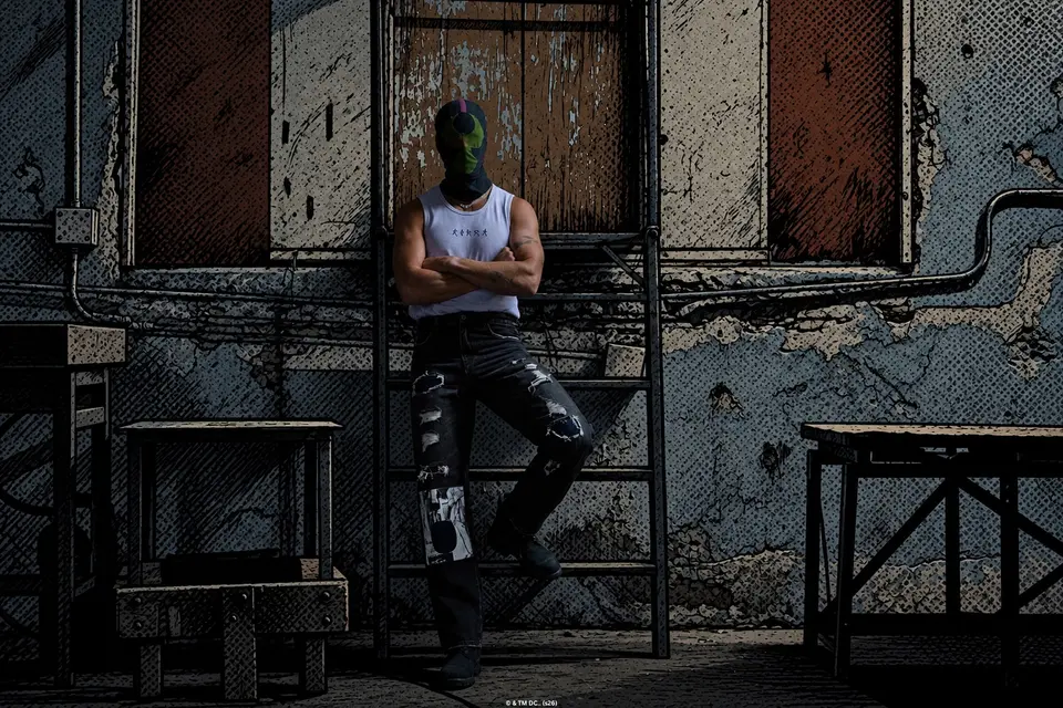Figure in the black Bane mesh face mask leaning against a ladder