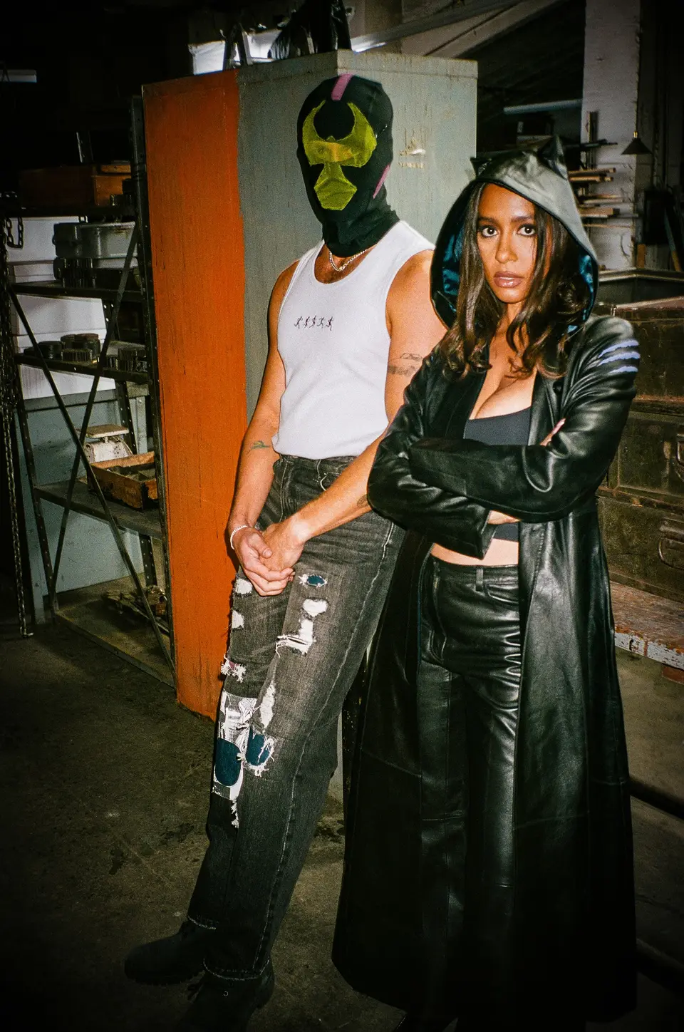 Bane mask and white tank beside a woman in the hooded Catwoman trench