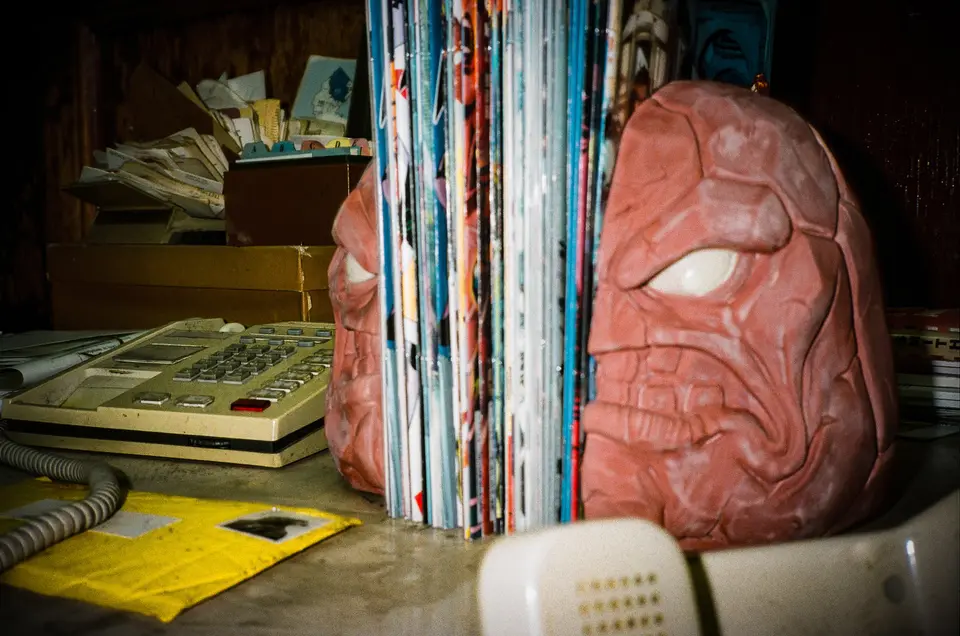 Close-up of a red Clayface bookend beside a row of comics