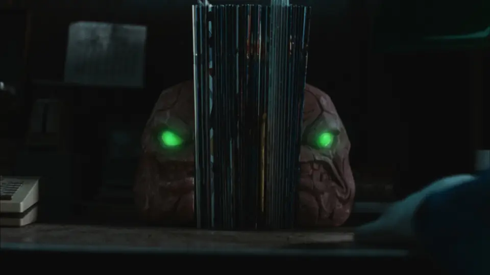 Film still: Clayface bookends with glowing green eyes in the dark