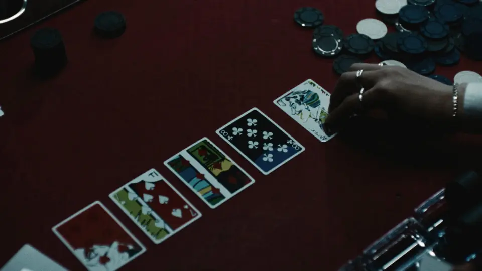 Film still: Joker playing cards laid out on a red poker table