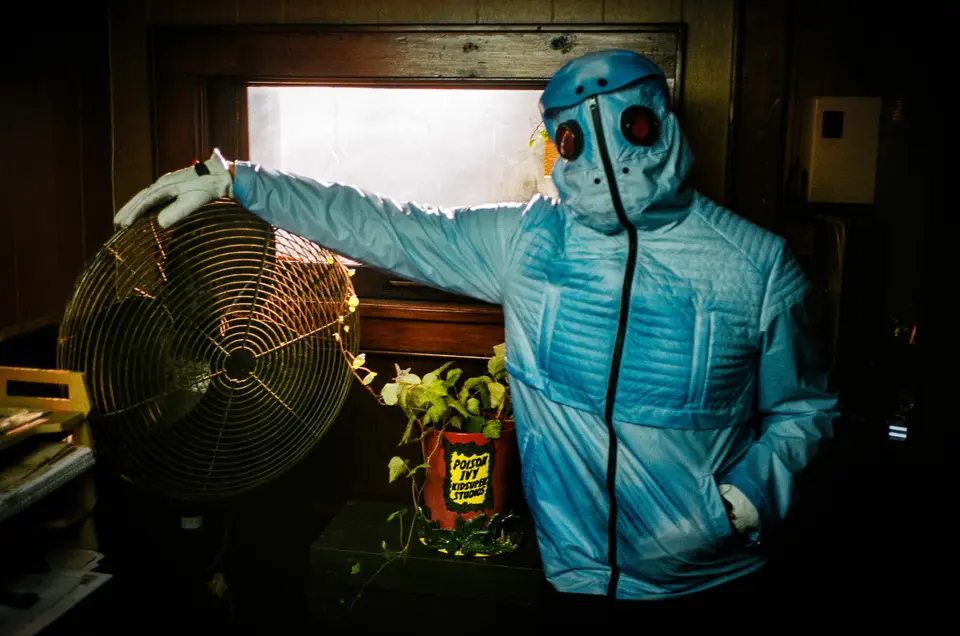 Mr. Freeze in the blue puffer and red goggles reaching for a desk fan